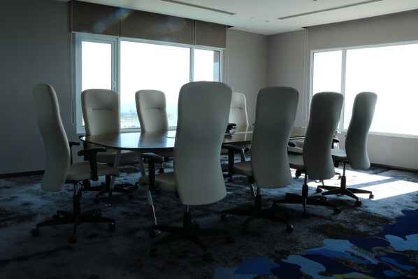 Une salle de conférence dotée d’une grande table et de six chaises, de grandes fenêtres offrant une vue dégagée et d’un revêtement de sol en moquette.