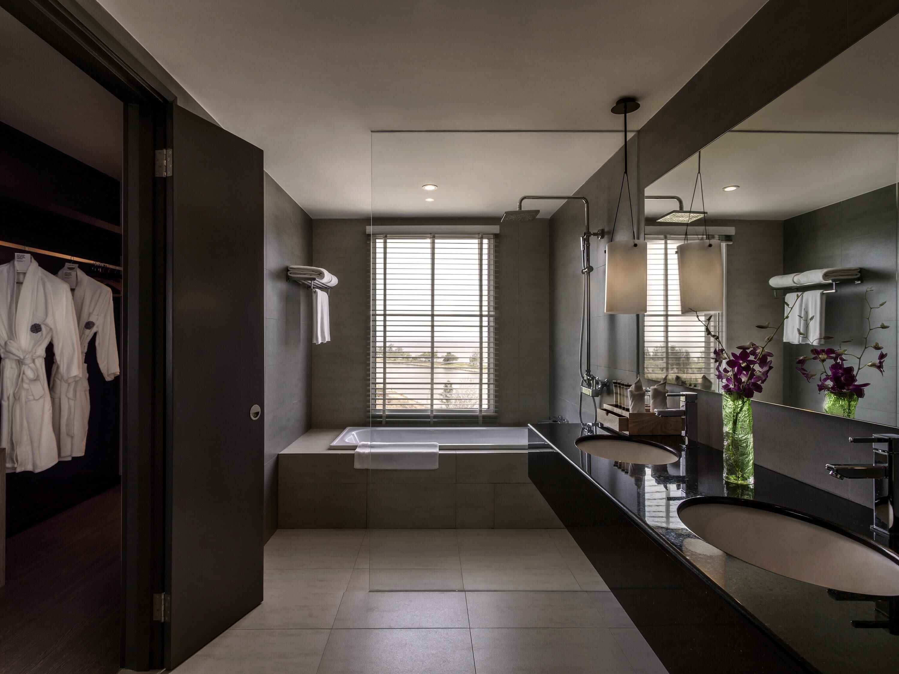 A modern bathroom with a large mirror, a bathtub, and a vanity with a sink.