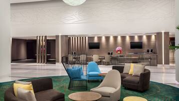 Een moderne lobby met zithoeken, een receptiebalie en een groot scherm.