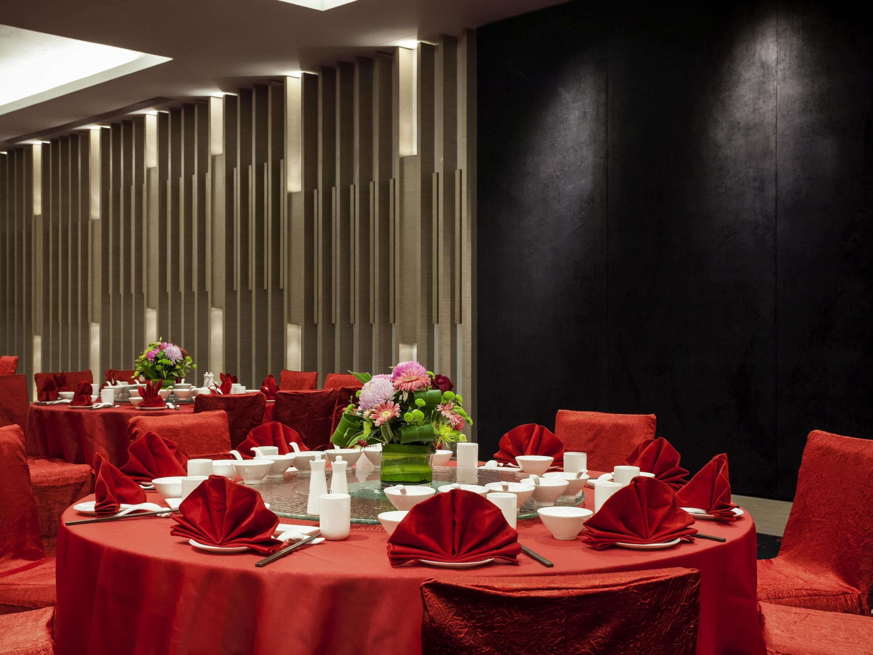 A dining area with round tables, red chairs, and a modern interior design.