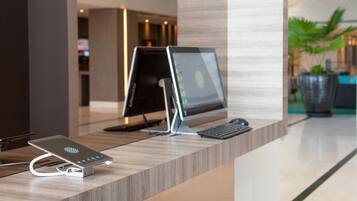 A reception desk with a desktop computer, a smartphone charging station, and a keyboard.