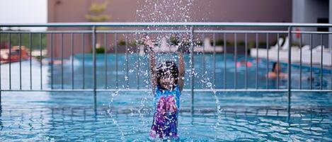 Un niño jugando en una piscina con agua salpicando.