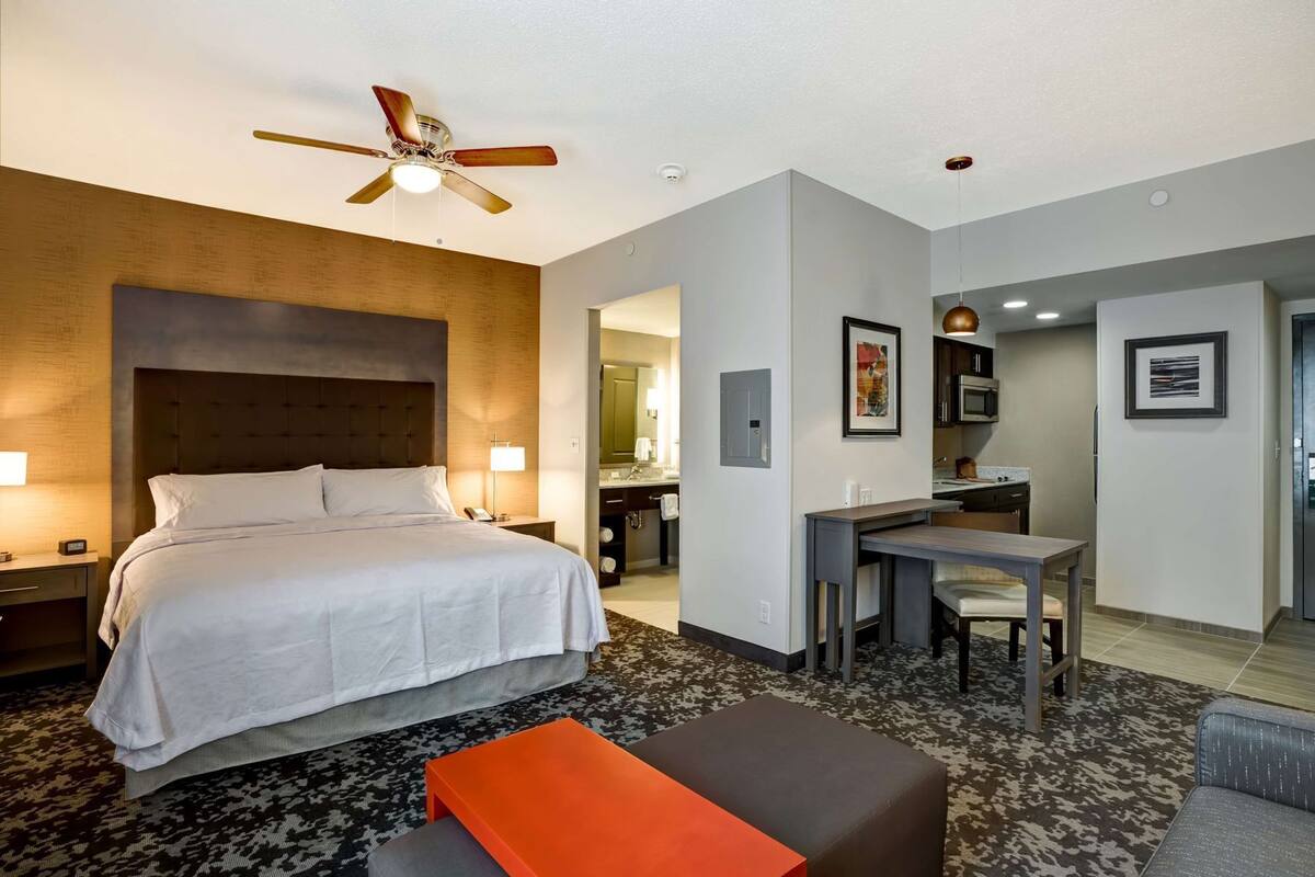 A hotel room with a bed, desk, chair, and a ceiling fan.