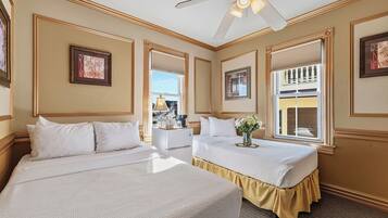 Quarto de hotel com duas camas, um ventilador de teto e vista para o exterior.