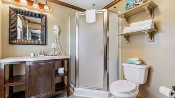 A bathroom with a walk-in shower, a toilet, a sink with a mirror, and a towel rack.