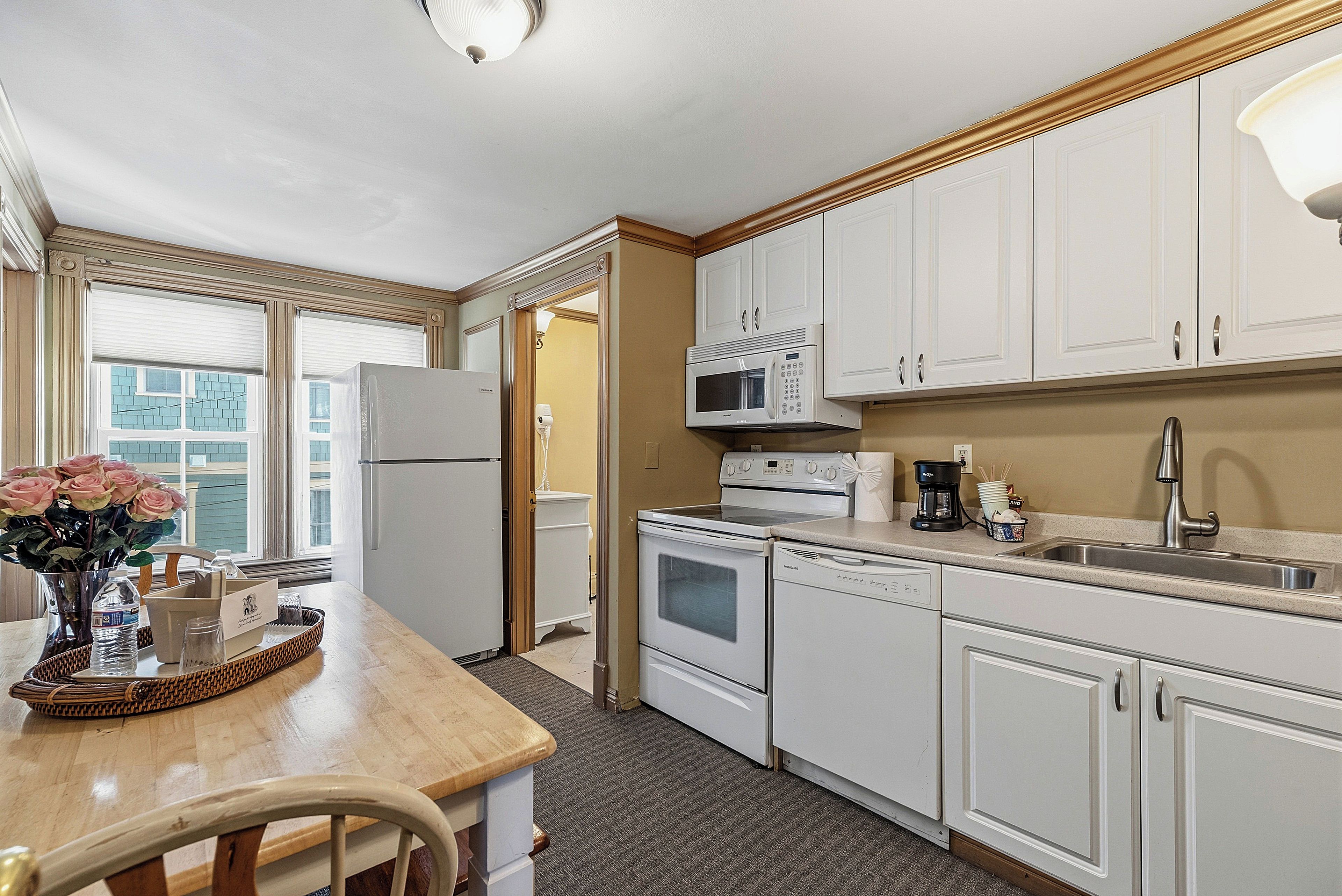 A kitchen with white cabinets, a refrigerator, a microwave, an oven, and a sink.