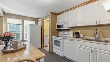 A kitchen with white cabinets, a refrigerator, a microwave, an oven, and a sink.
