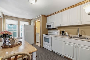 A kitchen with white cabinets, a refrigerator, a microwave, an oven, and a sink.