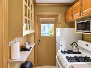 A compact kitchen with a stove, microwave, and refrigerator.