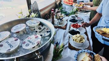 A buffet table with various food items including yogurt, fruits, and waffles.