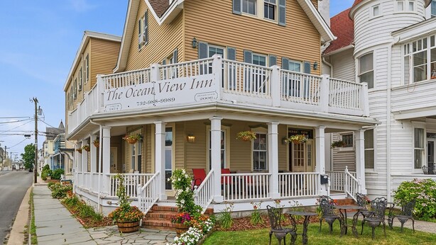 A two-story hotel with a balcony, a red roof, and a sign that reads 'The Ocean View Inn.'