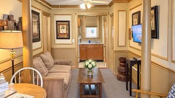 A living room with a sofa, a coffee table, a TV, and a dining area with a table and chairs.