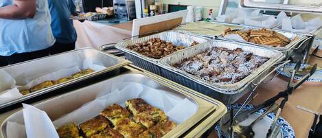 A buffet table with various food items, including casseroles, waffles, and pastries.