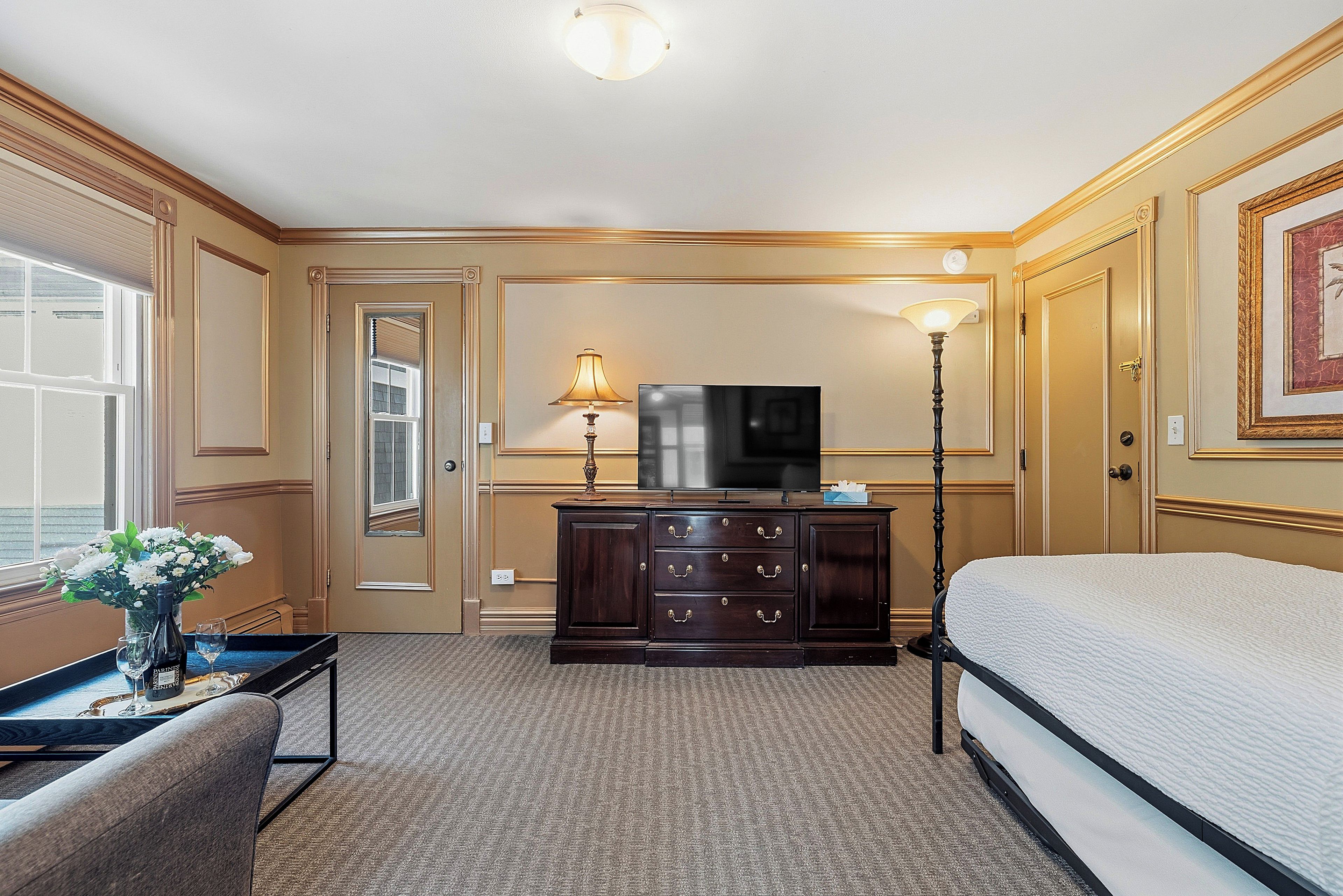 Ein Hotelzimmer mit Bett, Schminktisch, Fernseher, Schreibtisch mit Lampe und Fenster mit Blick.