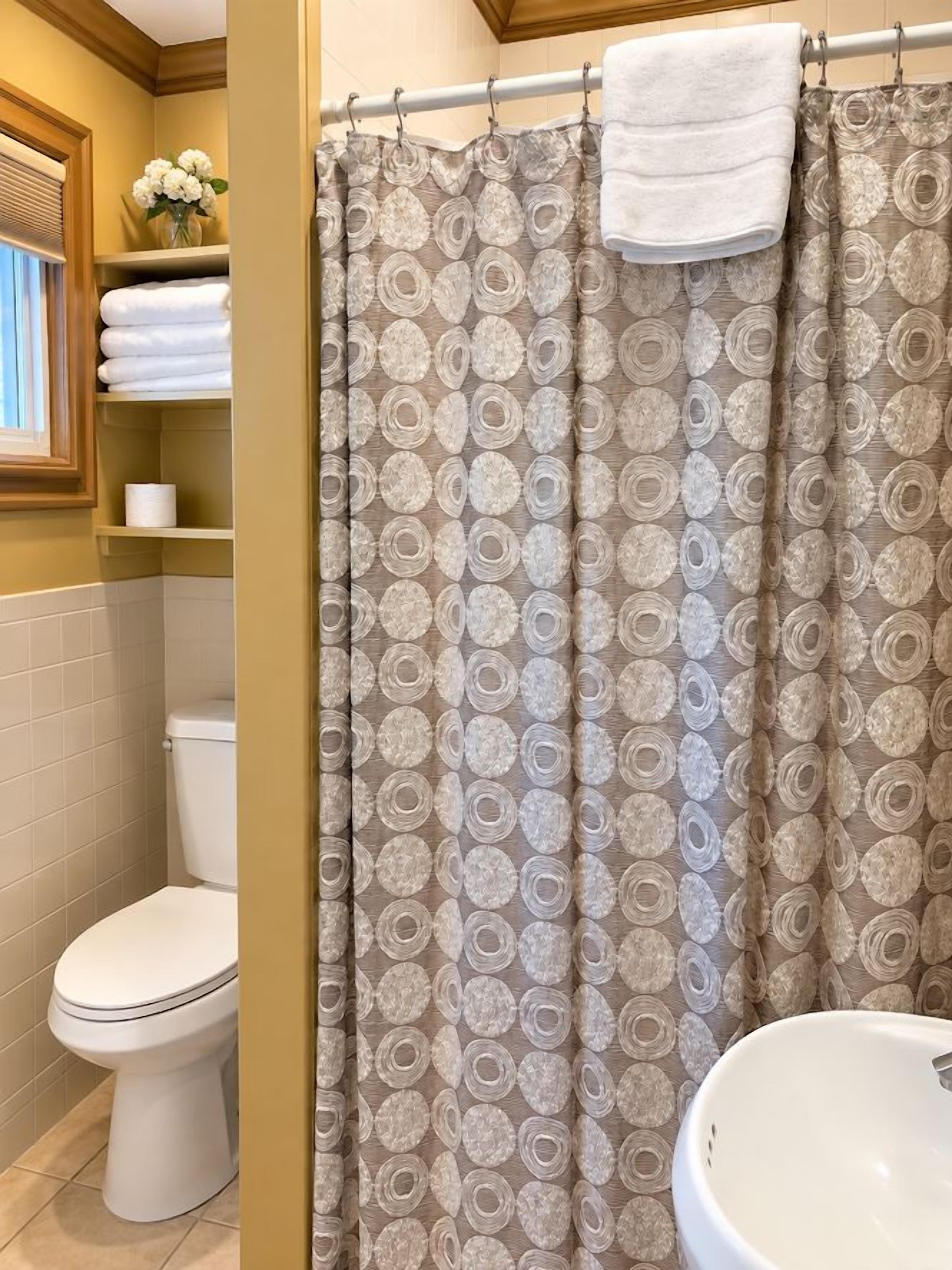 A bathroom with a toilet, a sink, and a shower curtain with a circular pattern.