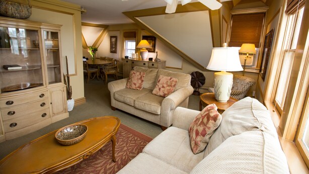 A living room with a sofa, a coffee table, and a dining area in the background.