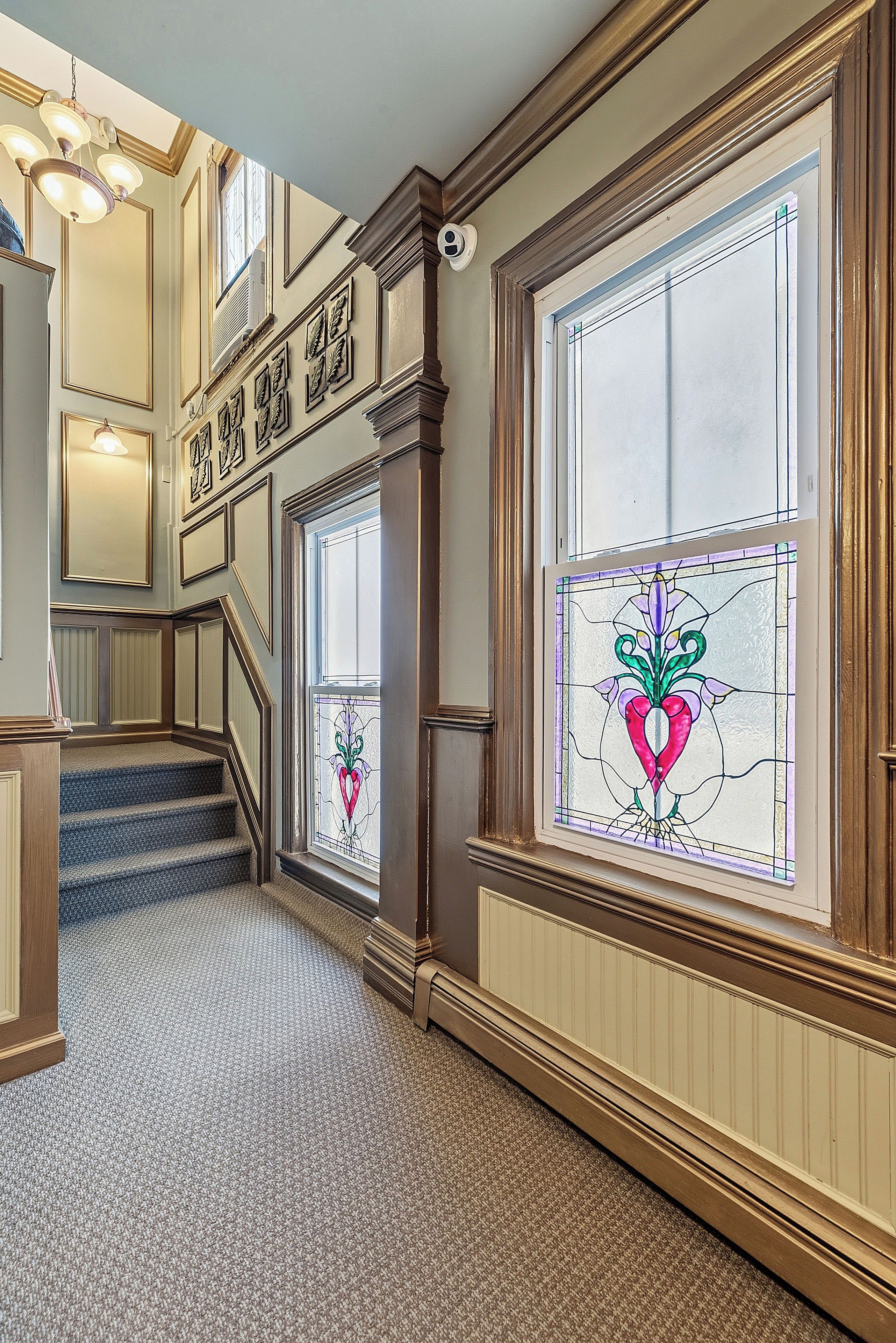 A grand staircase with a carpeted floor leading to a landing with a decorative sign.