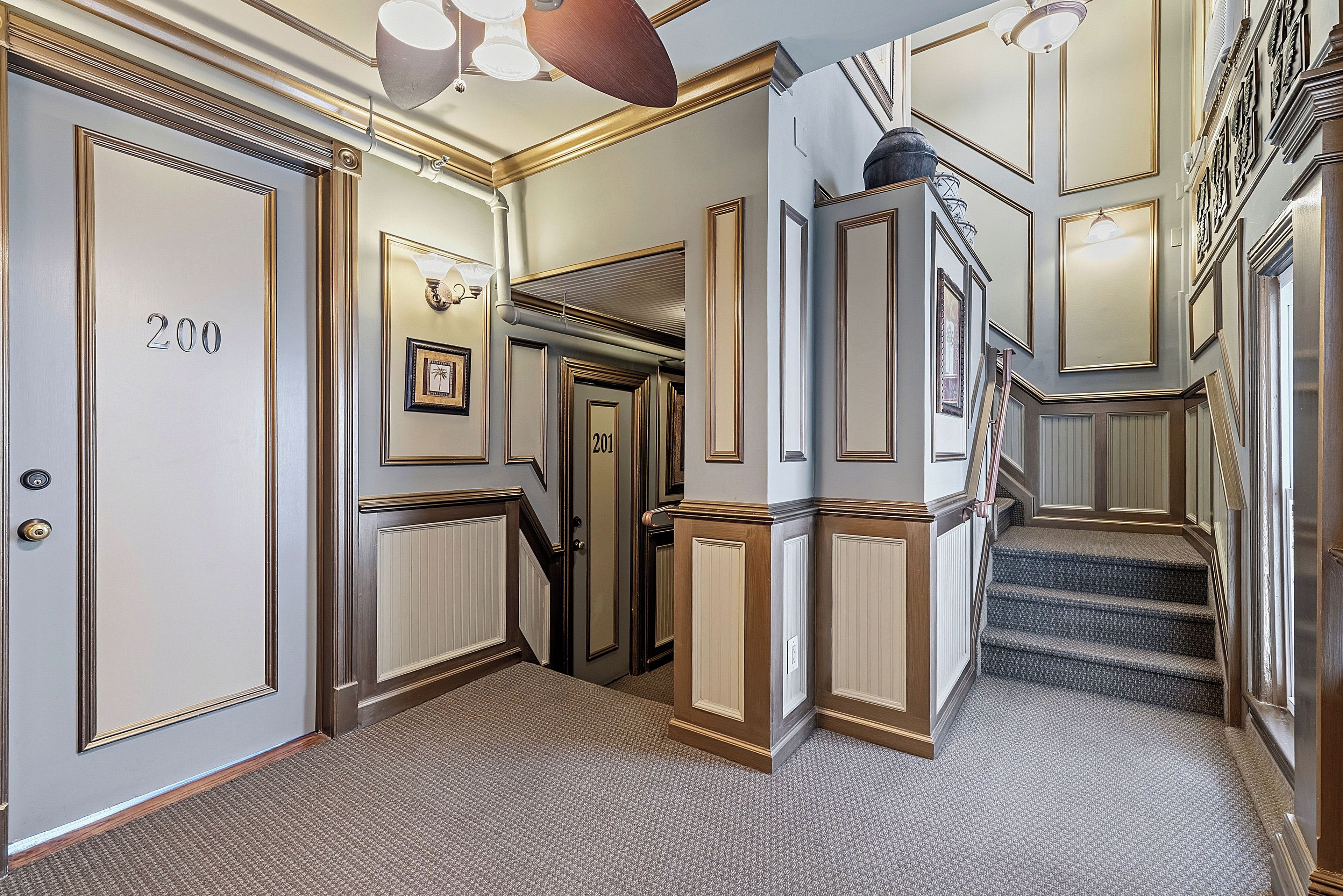 A hallway with doors numbered 200 and 201, carpeted floors, and a staircase.