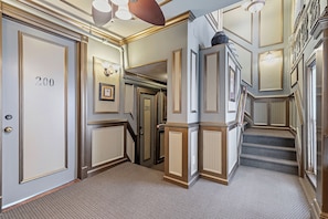 A hallway with doors numbered 200 and 201, carpeted floors, and a staircase.