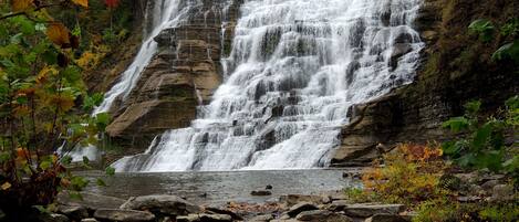 A waterfall cascading over rocky terrain with autumn foliage.