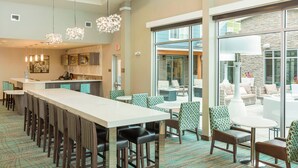 A hotel lobby with a long reception desk, multiple seating areas, and a view of the outdoor patio. - Residence Inn by Marriott Portland Hillsboro/Brookwood (Hillsboro)