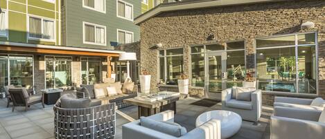 A modern outdoor patio with seating, a pool, and a stone facade.