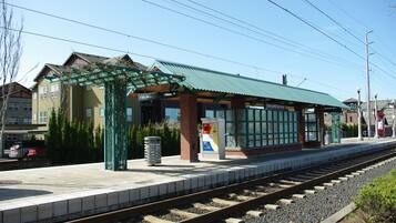 Andén de estación de tren con techo verde, una máquina para comprar billetes y un refugio.