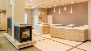 A modern hotel lobby with a fireplace, reception desk, and pendant lighting. - Residence Inn by Marriott Portland Hillsboro/Brookwood (Hillsboro)