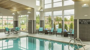 An indoor swimming pool with clear glass walls, wooden ceiling, and multiple lounge chairs. - Residence Inn by Marriott Portland Hillsboro/Brookwood (Hillsboro)
