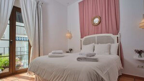 A bedroom with a bed, a window with curtains, a wall-mounted light, and a small shelf with a vase. - Hotel La Morada Mas Hermosa (Marbella)