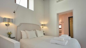 A bedroom with a large bed, two bedside lamps, a nightstand with a vase, and a door leading to another room. - Hotel La Morada Mas Hermosa (Marbella)
