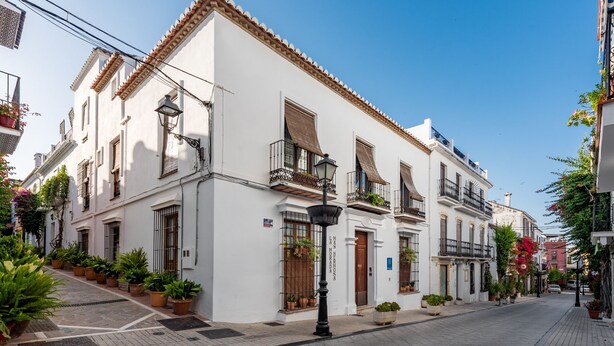 A white building with a tiled roof, multiple balconies, and potted plants on the ground floor. - Hotel La Morada Mas Hermosa (Marbella)