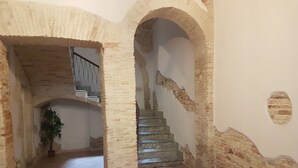 A staircase with a handrail, flanked by brick walls and arches, leading to an upper level. - Beni Benius (Cagliari)