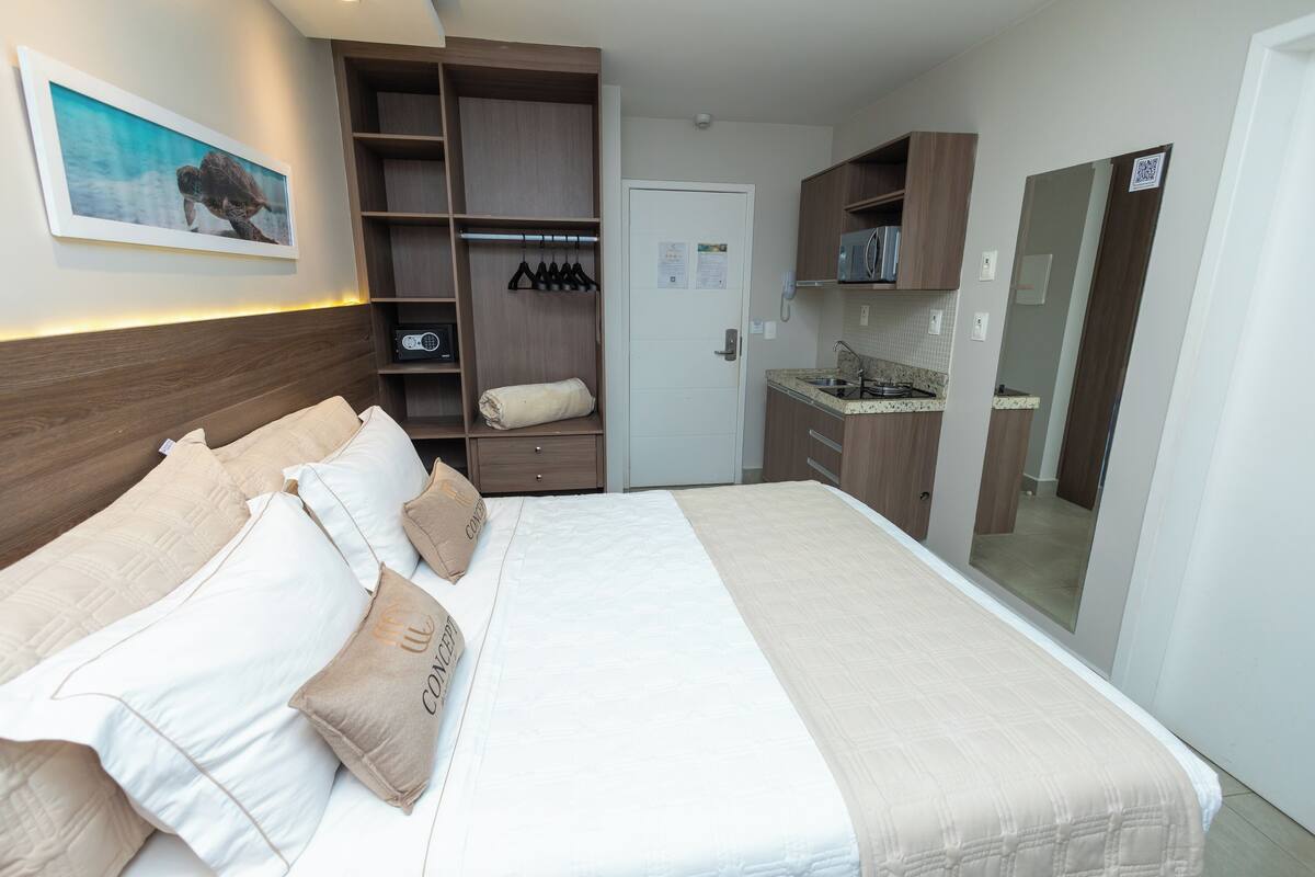 A hotel room with a bed, a wardrobe, a small kitchenette, and a bathroom.