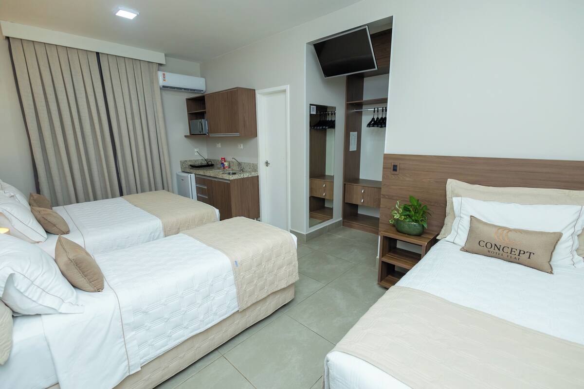 A hotel room with two beds, a TV, a minibar, and a closet.