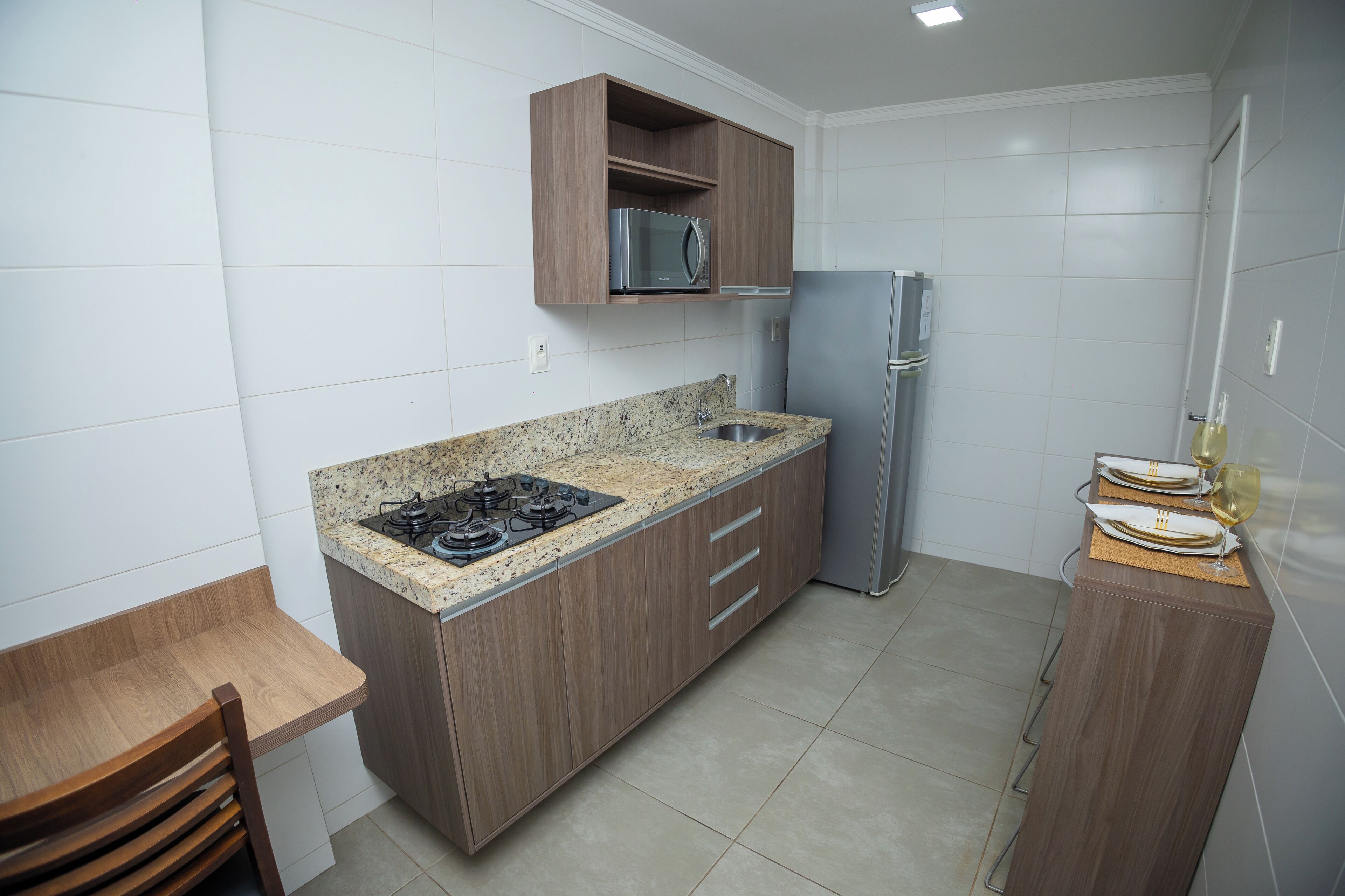 A compact kitchen with a built-in gas stove, a microwave, and a refrigerator.