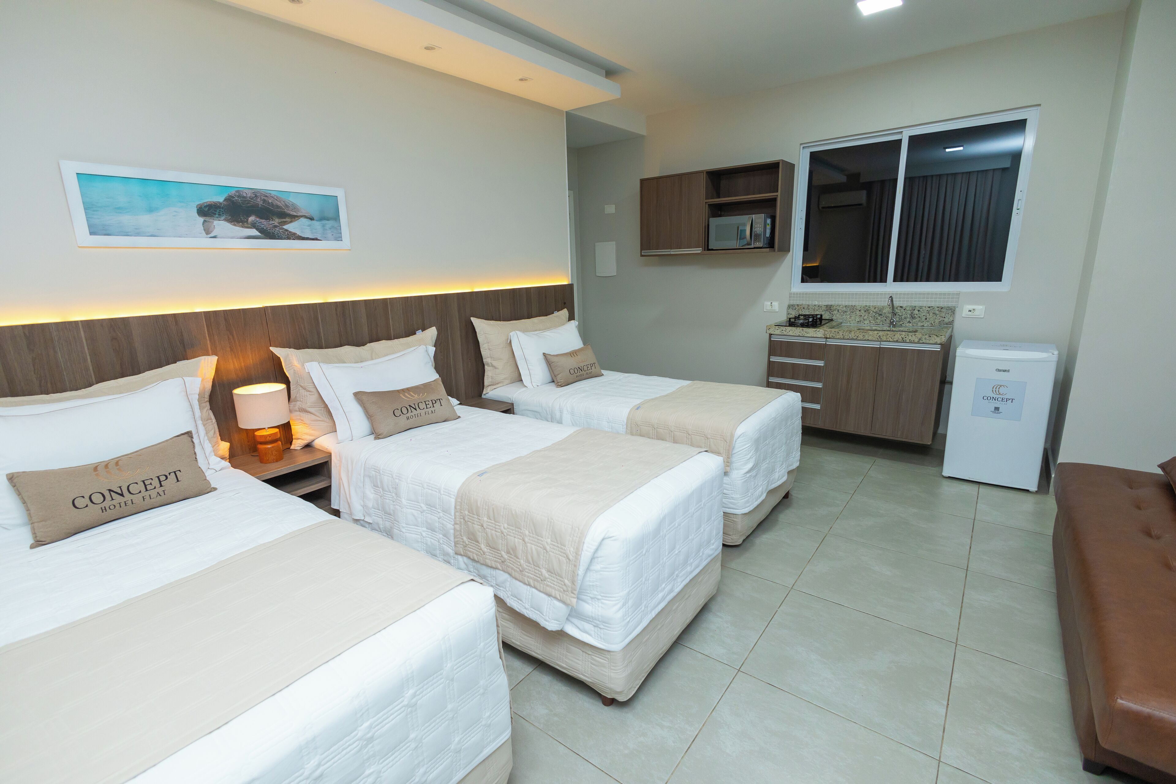 Habitació d'hotel amb dos llits, una cuineta i vista al mar.