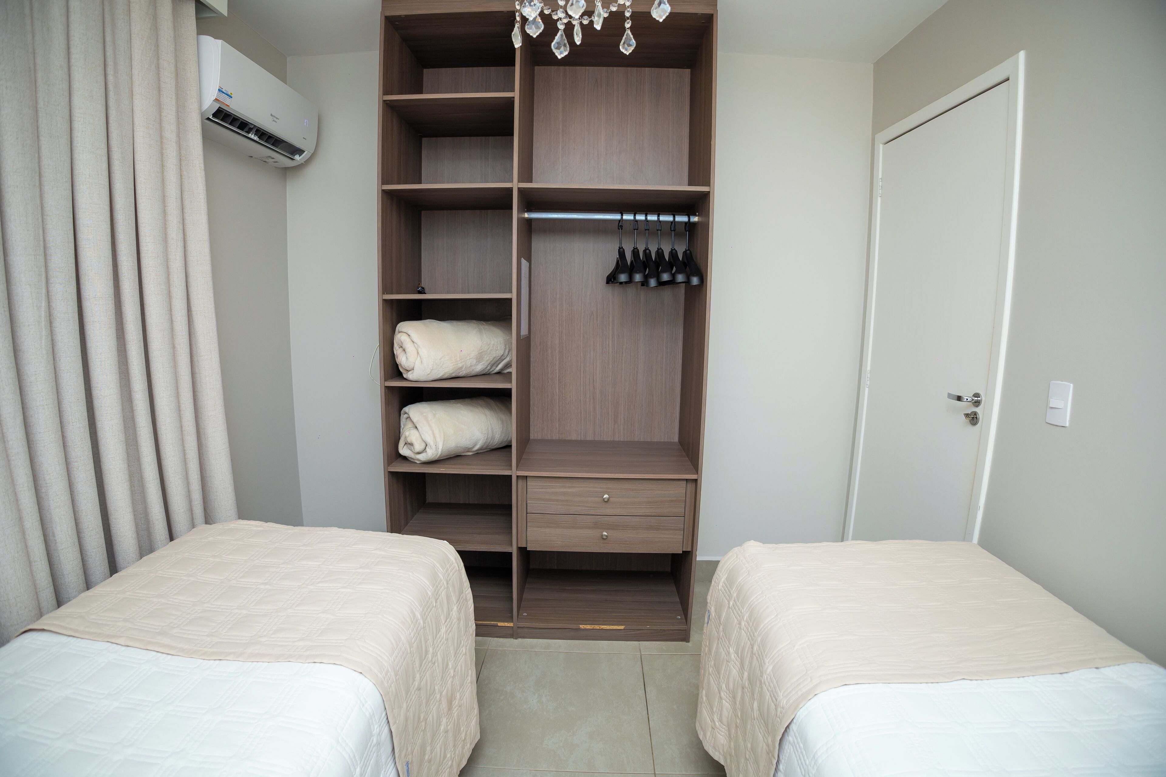A bedroom with two beds, a wardrobe, and an air conditioning unit.