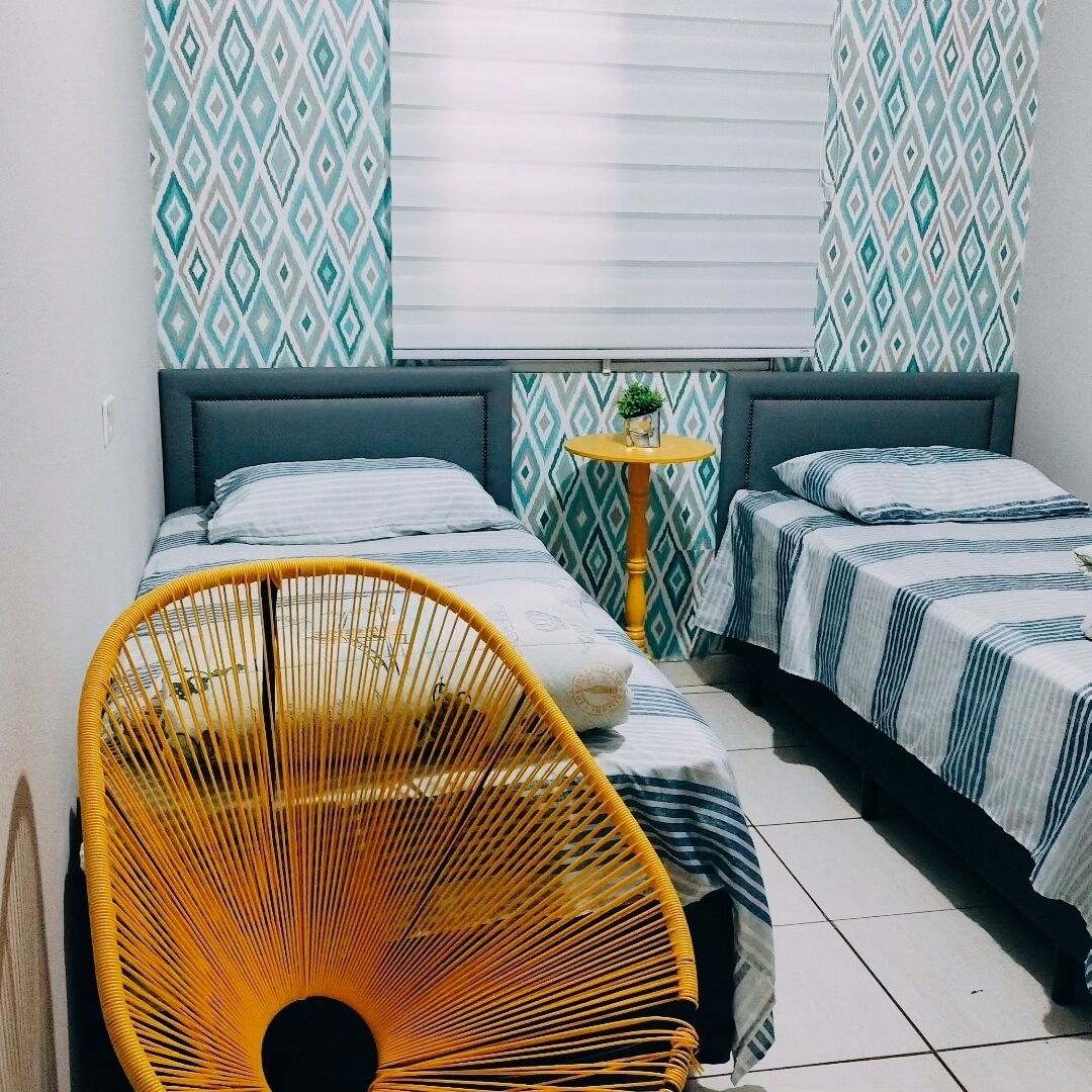 Une chambre avec deux lits, une petite table ronde et une chaise en osier.