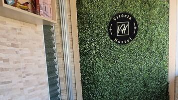 Ein Zimmer mit einem türkisfarbenen Sofa, einer grünen Wand mit einem Logo und einem Fenster mit Jalousien.