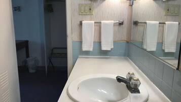 Een badkamer met een wit wastafel, een spiegel en twee handdoekrekken met witte handdoeken.
