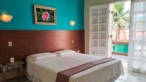 A hotel room with a bed, a nightstand, a painting, and a view of the outside. - Pousada Larissa (Paraty)