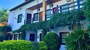 A two-story building with a white facade, wooden balconies, and a garden area with greenery. - Pousada Larissa (Paraty)