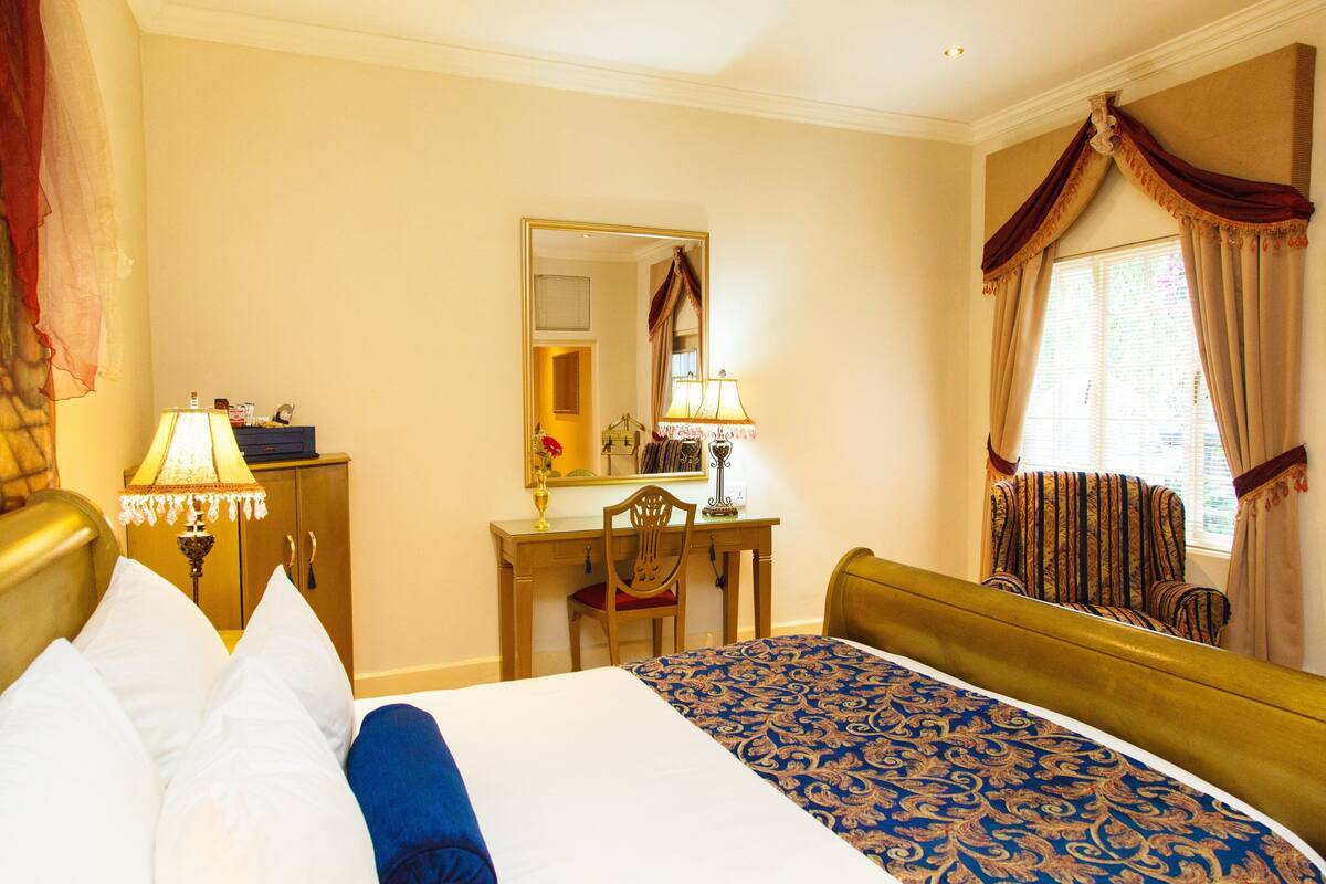 A hotel room with a bed, a desk, a chair, and a window with curtains.