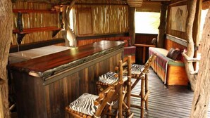 Un coin bar rustique en bois, avec un comptoir en bois et des chaises à rayures zébrées.