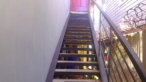 A wooden staircase with metal railings leading to a red door at the top.