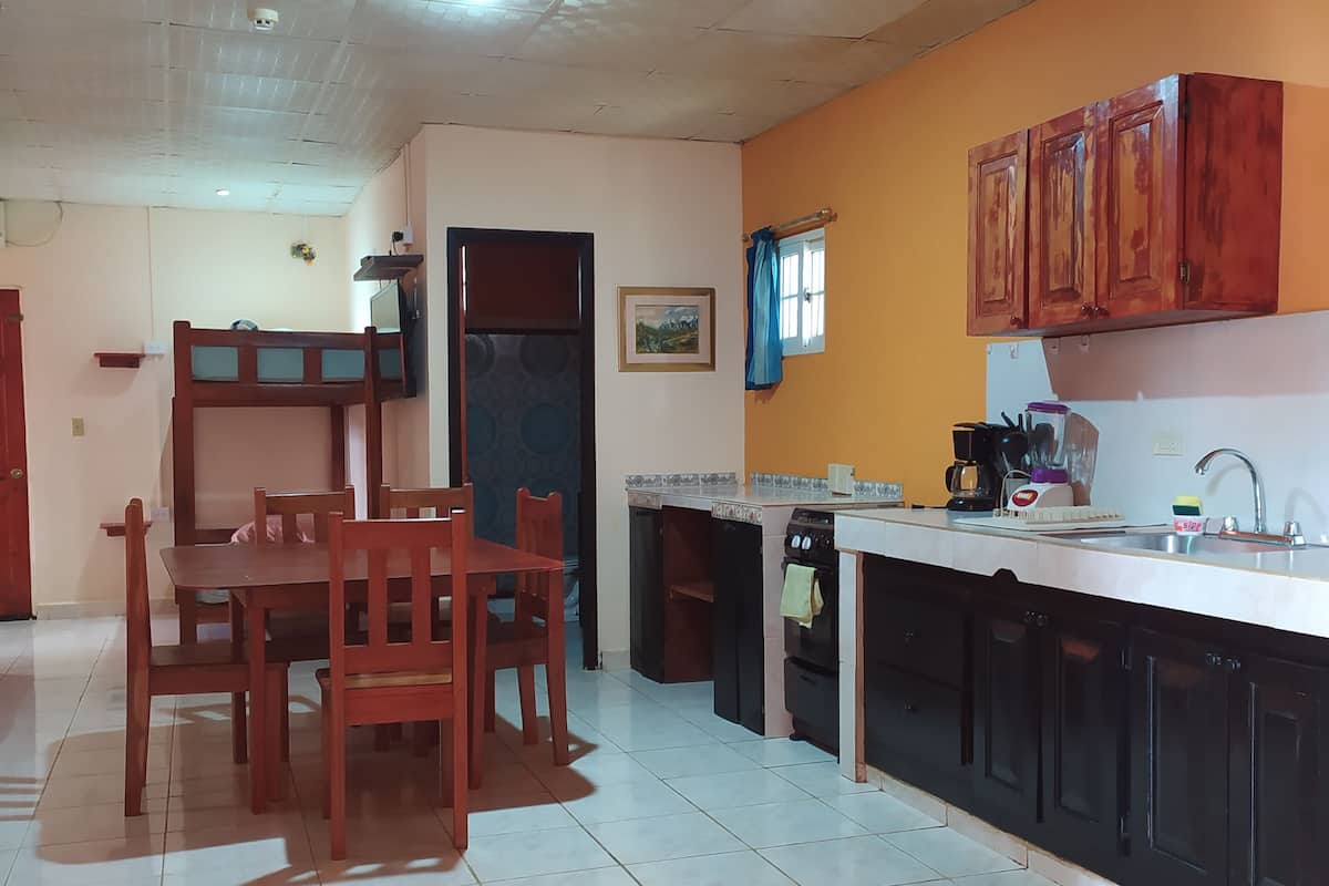 A kitchen with a dining area, featuring a tiled floor, wooden furniture, and a built-in oven.