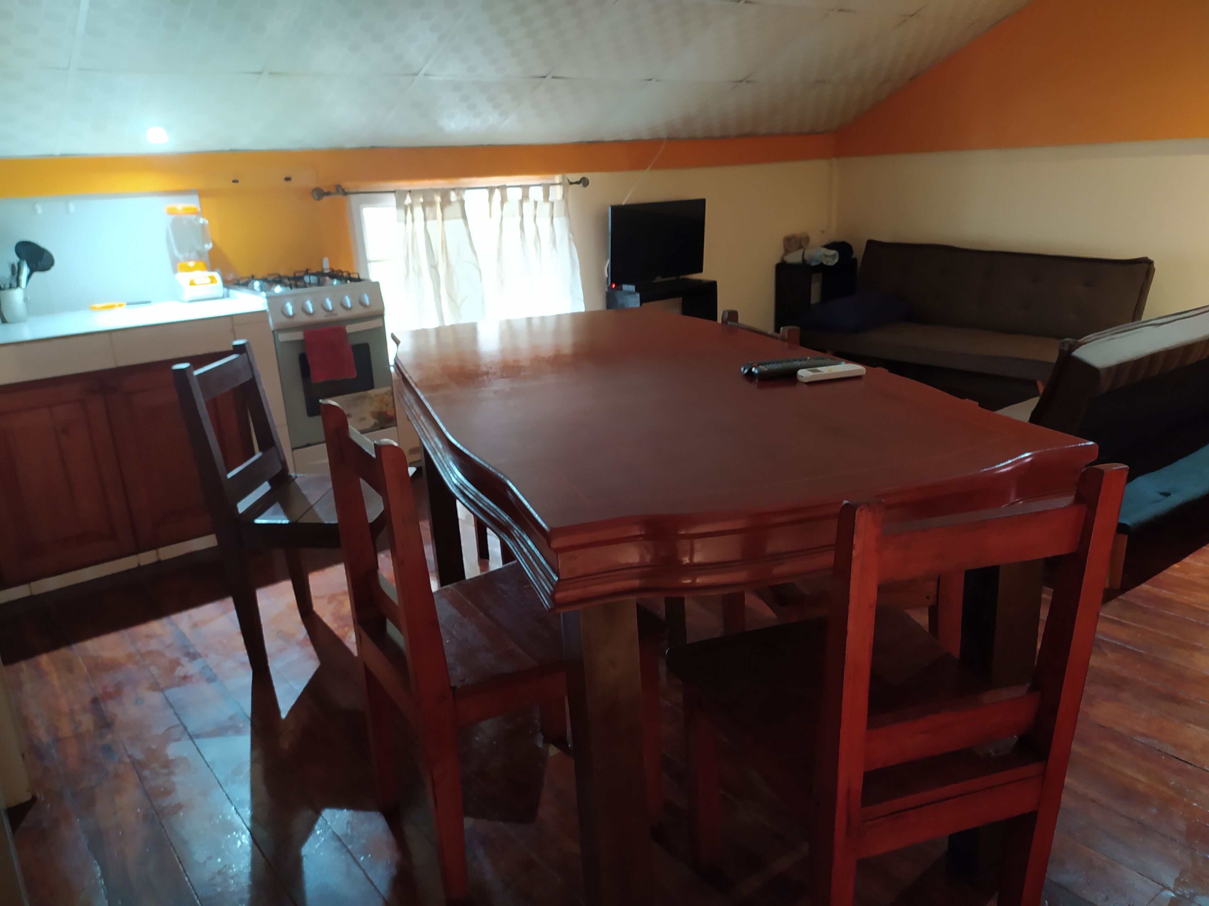 A kitchen with a dining table, chairs, a stove, and a television.