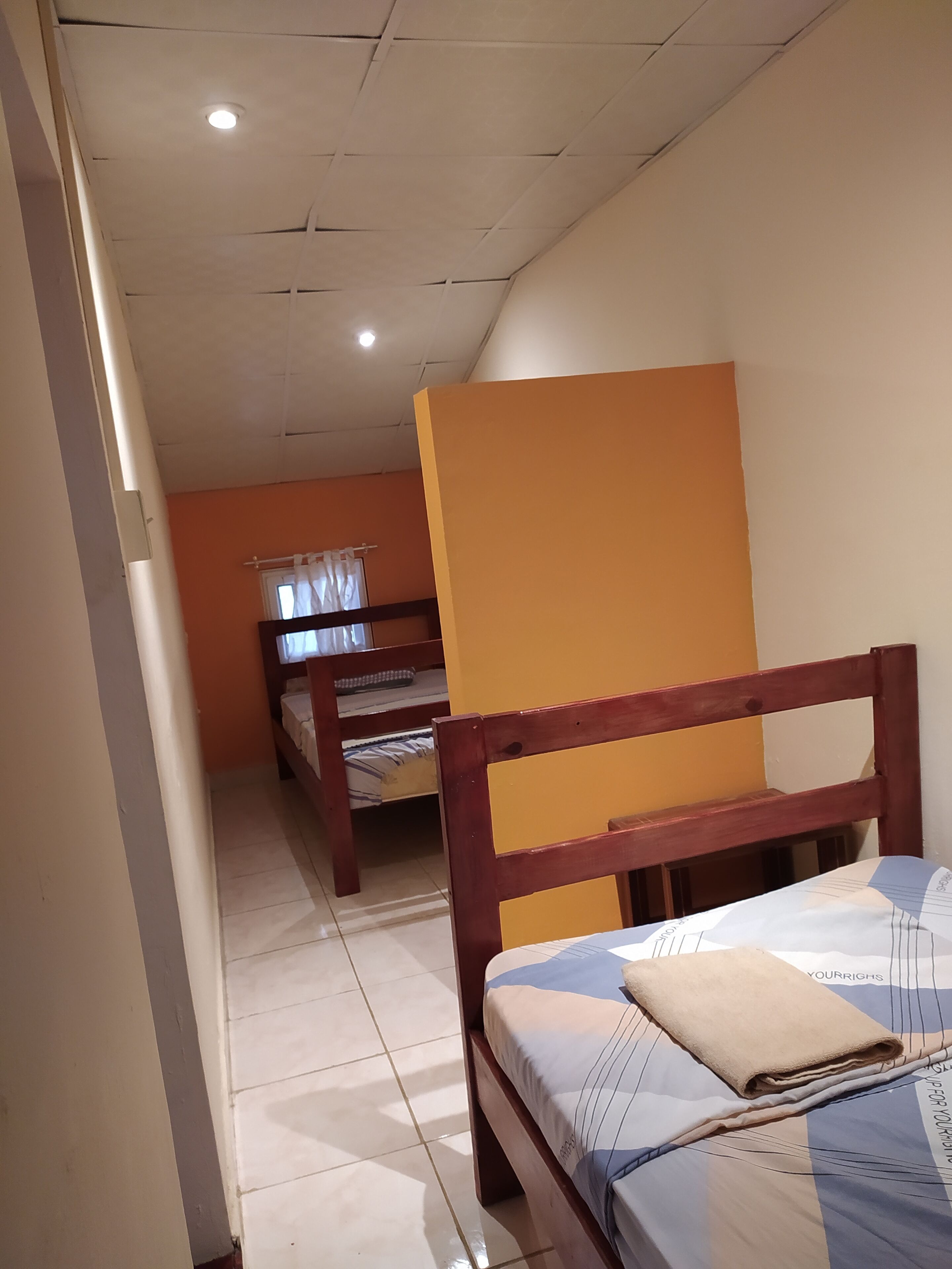 Una habitació de dormitori amb dos llits superposats, un capçal de llit de fusta i una paret taronja senzilla.