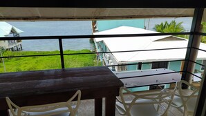 A balcony with a table and chairs, overlooking a body of water and buildings.